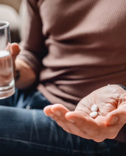Holding glass of water and pills for oral conscious sedation in Dallas, TX