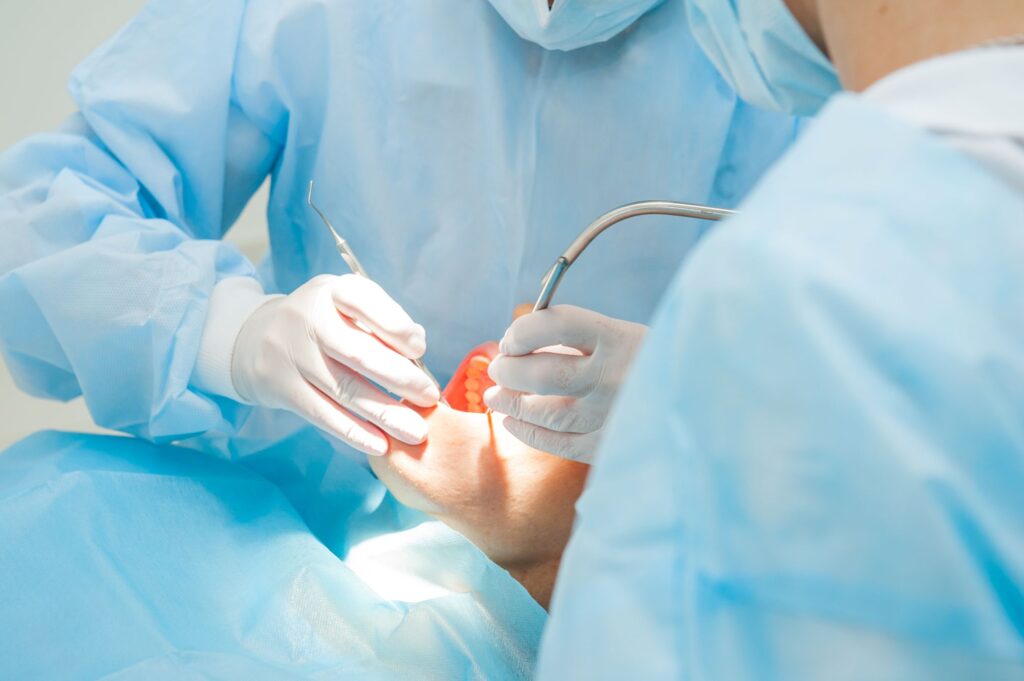 Dentists in blue scrubs performing oral surgery